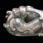 AN INLAID SILVER GARMENT HOOK CAST WITH A MYTHICAL BEAST