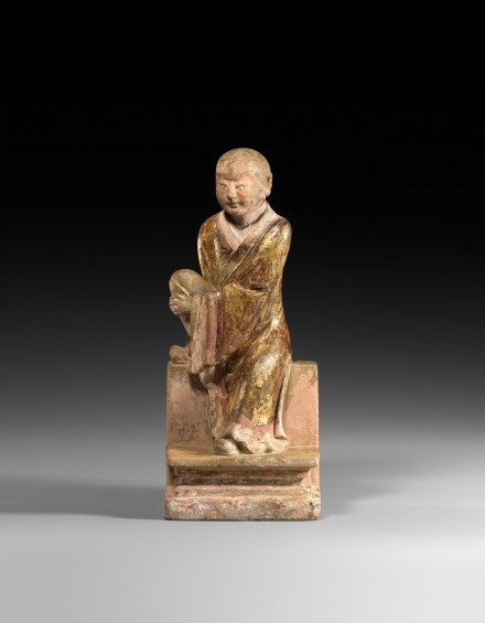 A PAINTED AND GILDED STONE FIGURE OF A LUOHAN