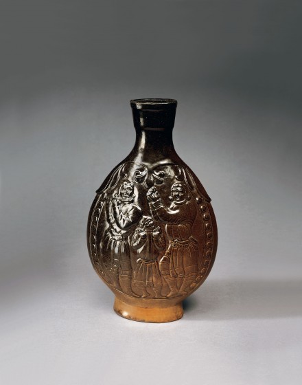 AN OLIVE-BROWN GLAZED RED POTTERY FLASK WITH FIGURAL DECORATION