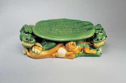 A LARGE SANCAI-GLAZED POTTERY PILLOW SUPPORTED ON LIONS