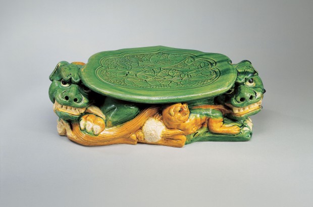 A LARGE SANCAI-GLAZED POTTERY PILLOW SUPPORTED ON LIONS