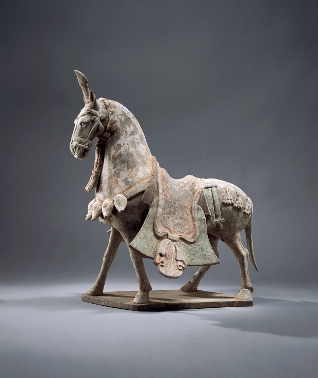 A PAINTED POTTERY CAPARISONED STRIDING HORSE