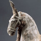 A PAINTED POTTERY CAPARISONED STRIDING HORSE