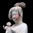 A LARGE PAINTED POTTERY COURT LADY HOLDING A CHILD