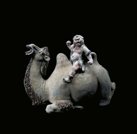 A LARGE PAINTED POTTERY KNEELING CAMEL AND RIDER