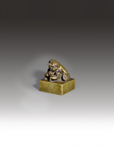 A BRONZE WEIGHT SURMOUNTED BY A BUDDHIST LION AND CUB