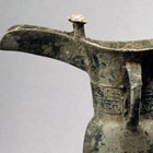 A BRONZE TRIPOD LIBATION CUP (JUE)