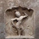 A LIMESTONE BLOCK WITH DANCER IN A NICHE