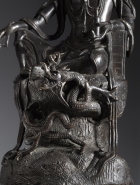 A BRONZE SEATED GUANYIN WITH A DRAGON