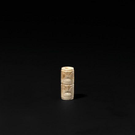 A CARVED NEOLITHIC JADE CYLINDRICAL BEAD