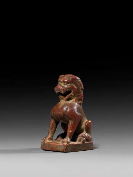 A SMALL RED SANDSTONE SEATED FIGURE OF A LION