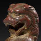 A SMALL RED SANDSTONE SEATED FIGURE OF A LION