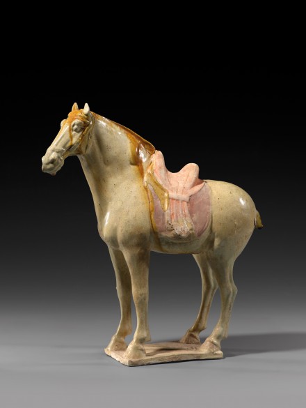 A GLAZED POTTERY FIGURE OF A SADDLED HORSE