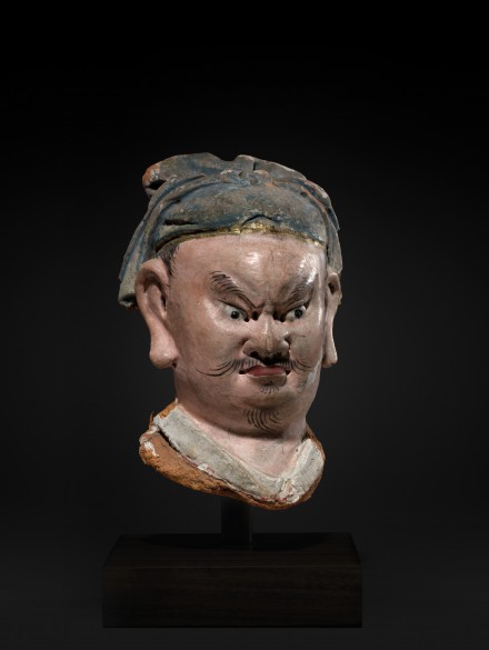 A PAINTED STUCCO HEAD OF A GUARDIAN