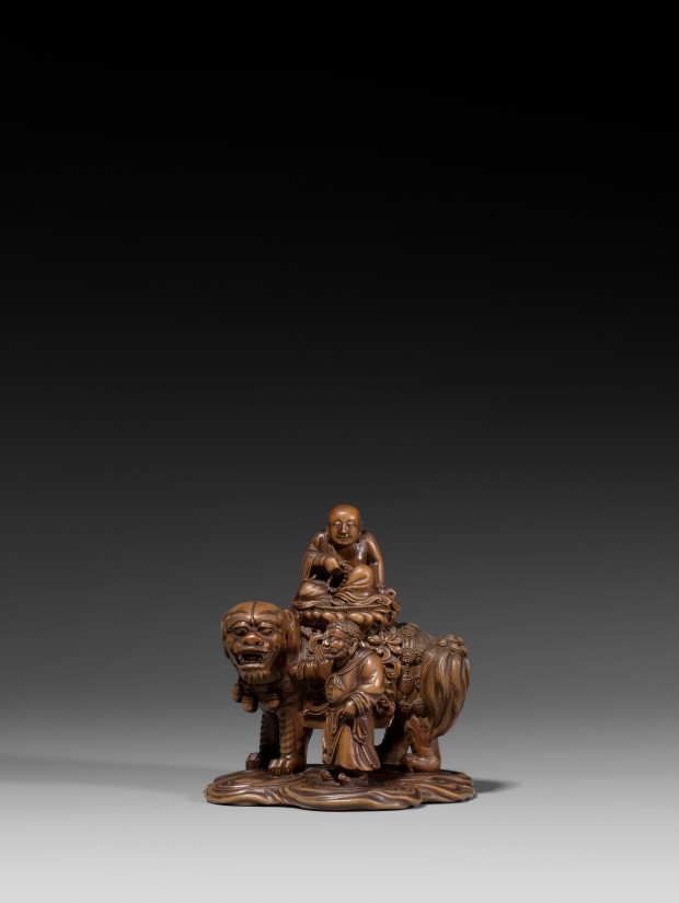 AN IMPERIAL BOXWOOD CARVING OF MANJUSHRI SEATED ON A LION