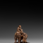 AN IMPERIAL BOXWOOD CARVING OF MANJUSHRI SEATED ON A LION