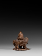 AN IMPERIAL BOXWOOD CARVING OF MANJUSHRI SEATED ON A LION